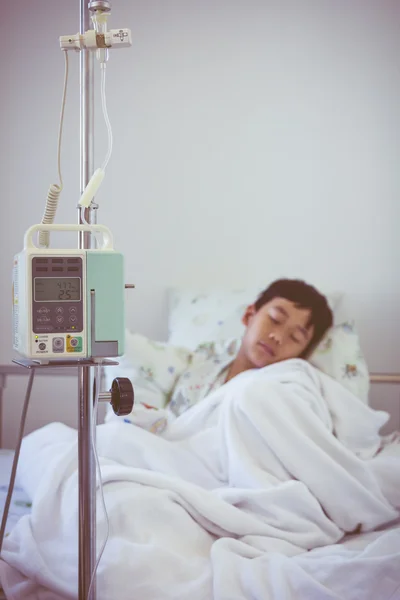 Asian boy sleeping on sickbed with infusion pump intravenous IV drip.