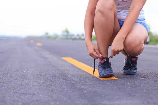 Stock Photo - Close up of girl tying her running shoe laces at s