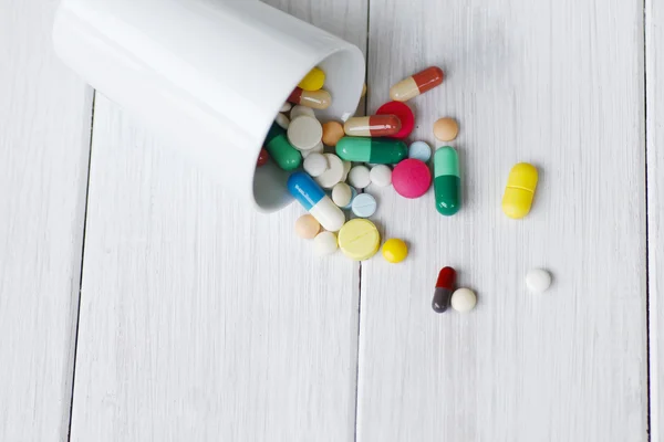 Stock Photo Pill bottle spilling pills on to surface isolated on a white background