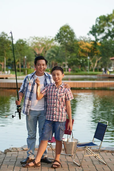 Boy and father showing fish