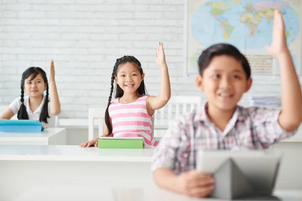 Children rising hands up to answer question