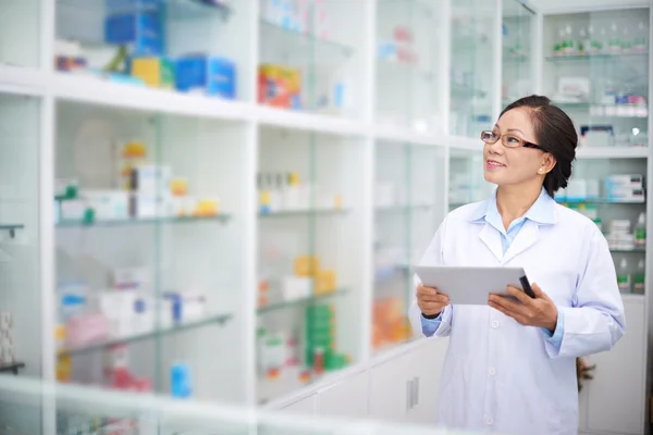 Pharmacist cheking drugs on shelves