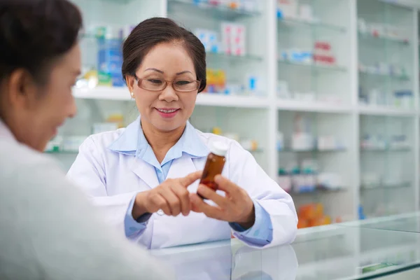 Pharmacist reading recommended dose of medication