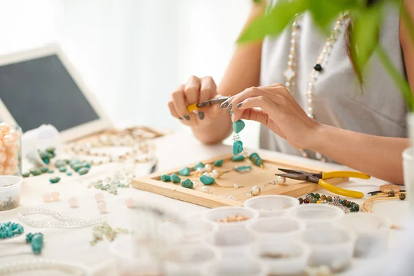 Woman using pliers when assembling earring