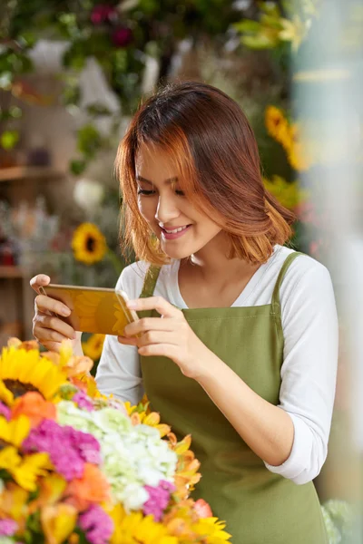 Florist taking photo of bouquet