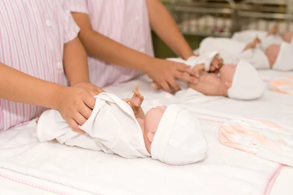 Hands dressing the baby dolls