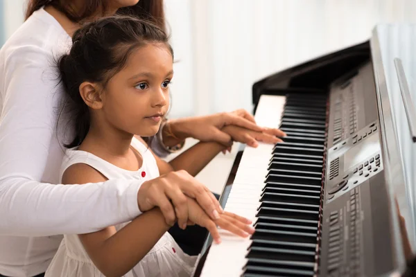 Woman helping daughter to play piano