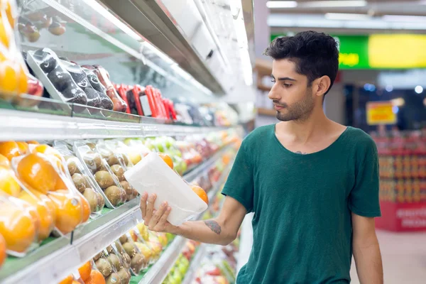 Young man choosing oranges