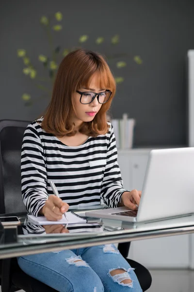 Woman   copying information out from  computer