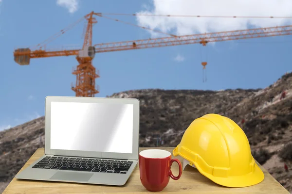 Laptop, hardhat with construction background