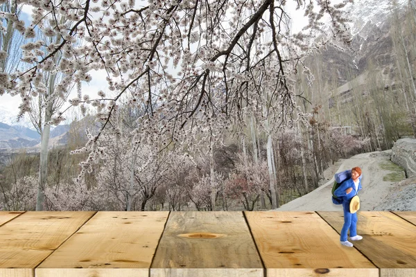 Backpacker miniature figure on wood table with nature scene