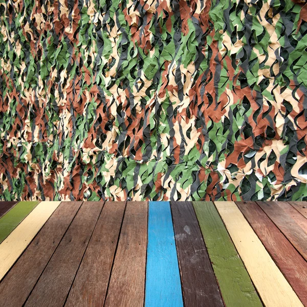 Wood table top on camouflage fabric background montage concept