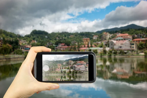 Taking photo on smart phone. building along lake in sapa city,