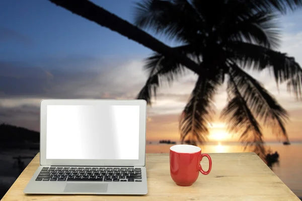 Laptop and red mug on wood table with Koh Tao seascape, Thailand