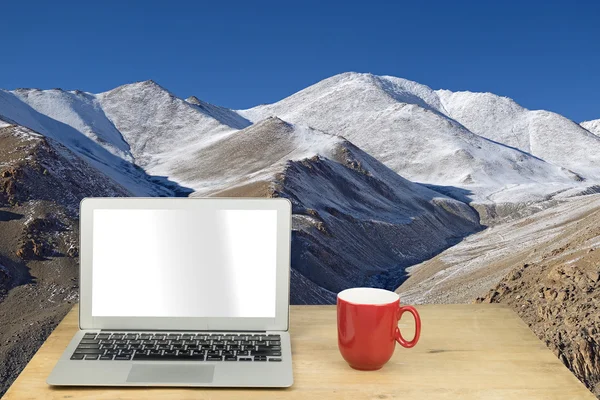 Laptop and red mug on wood table with mountain in Leh ladakh, In