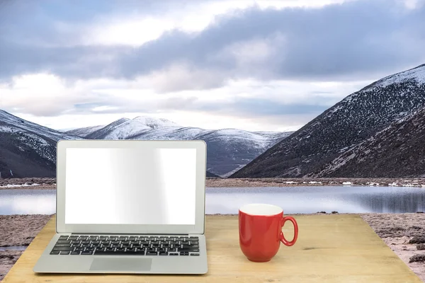 Laptop and red mug on wood table with Yading, China