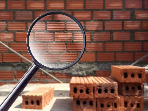 Magnifying glass over wall brick in construction site