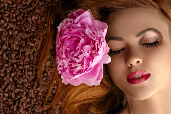 Beautiful woman face with peony on coffee beans