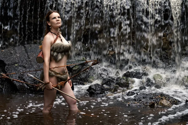 Archer stands in the water with the bow and arrow