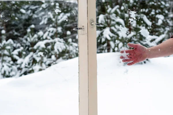 Hand throwing snow in the wooden windows