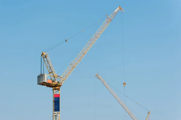 Industrial construction cranes at construction site with clear sky background