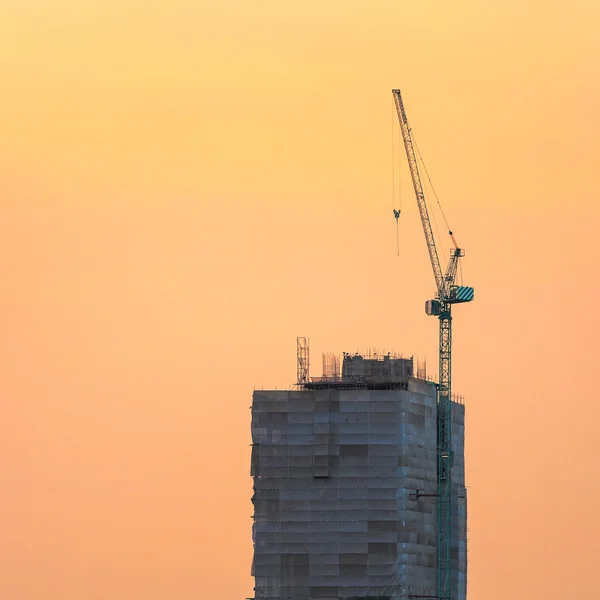 Industrial construction cranes at construction site with sunset sky background