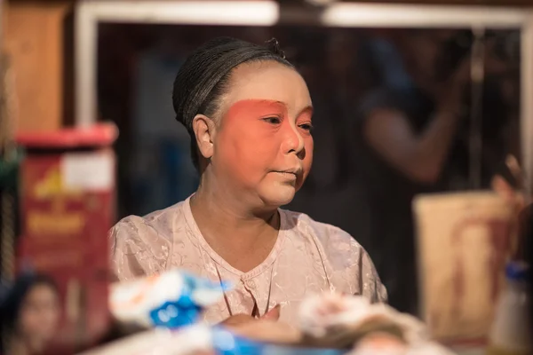 A Chinese opera actress painting mask on her face before the performance at backstage at major shrine in Bangkok's chinatown on October 16, 2015 in Bangkok,Thailand