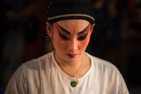 A Chinese opera actress painting mask on her face before the performance at backstage at major shrine in Bangkok\'s chinatown on October 16, 2015 in Bangkok,Thailand