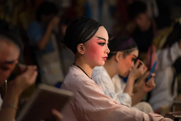 A Chinese opera actress painting mask on her face before the performance at backstage at major shrine in Bangkok's chinatown on October 16, 2015 in Bangkok,Thailand