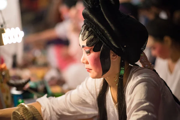 A Chinese opera actress painting mask on her face before the performance at backstage at major shrine in Bangkok\'s chinatown on October 16, 2015 in Bangkok,Thailand