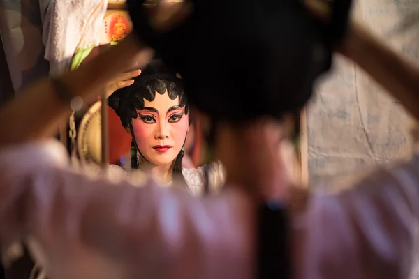 A Chinese opera actress painting mask on her face before the performance at backstage at major shrine in Bangkok\'s chinatown on October 16, 2015 in Bangkok,Thailand