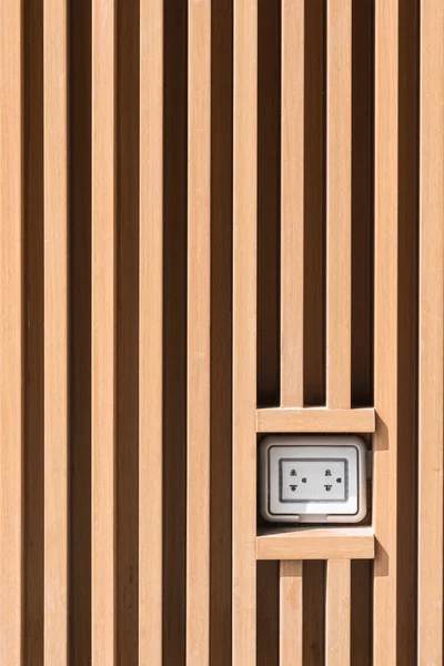 Plug socket on light brown wooden wall pattern at outdoor installation