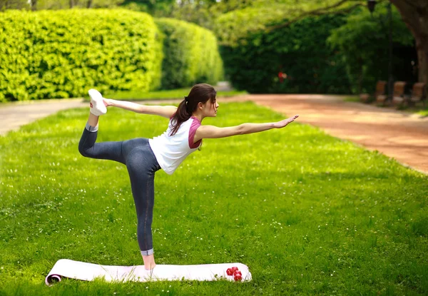 Sportive young woman stretching, doing exercises balancing