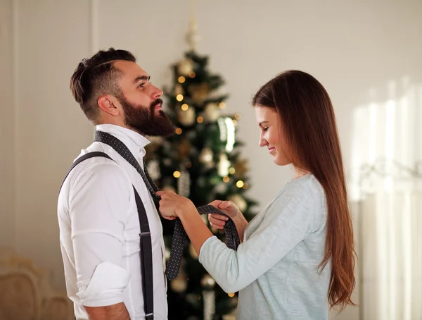 Girl clothe her boyfriend tie on background Christmas trees