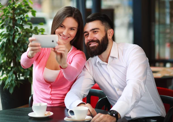 Happy couple taking photo with mobile phone in cafe