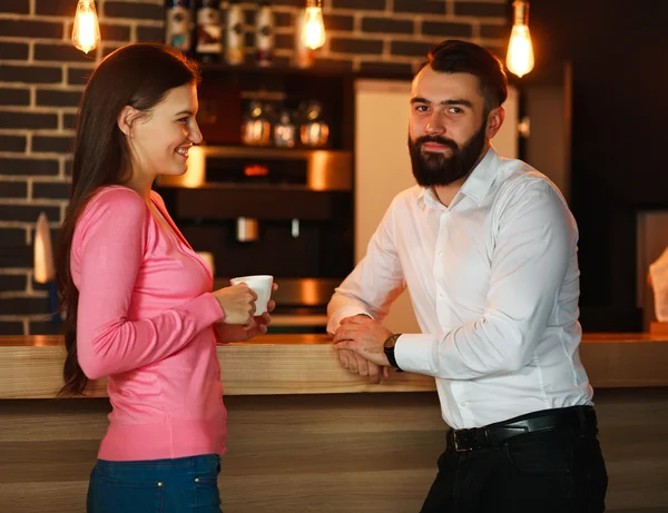Young happy couple met in bar and talking with a cup of coffee