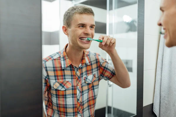 Man cleans teeth in the bathroom