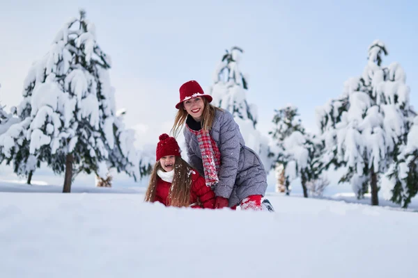 Daughter with mother play in snow-covered park