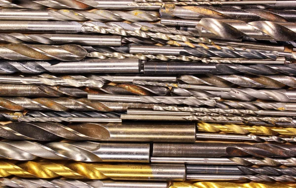 Many old dirty used metal drill bits as background