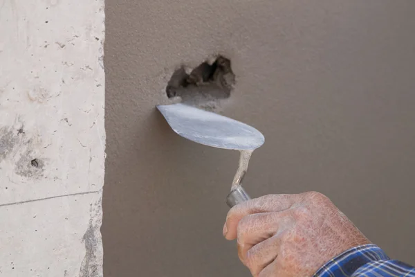 Hand using trowel to finish wet concrete wall at construction si