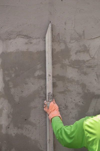 Hand using trowel to finish wet concrete wall at construction si