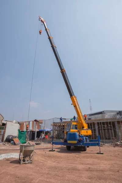 Crane lifting concrete mixer container at construction site