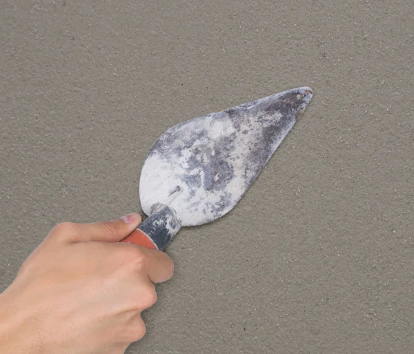 Hand of worker use trowel plastering concrete at wall