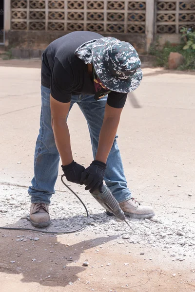 Worker repairing and drilling concrete road