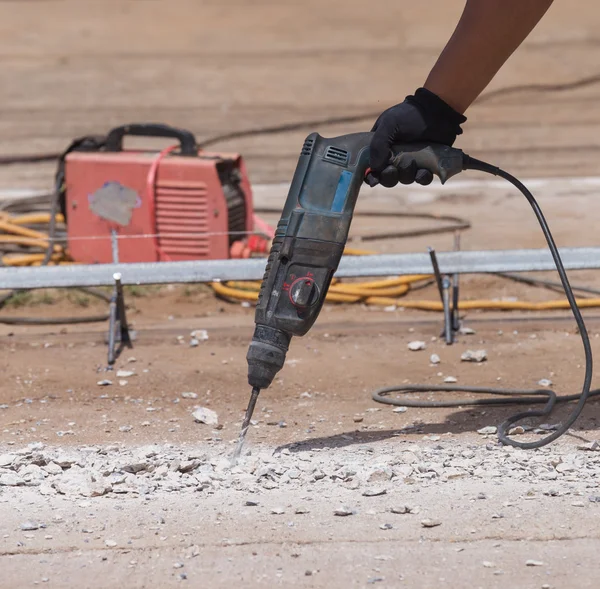 Worker repairing and drilling concrete road