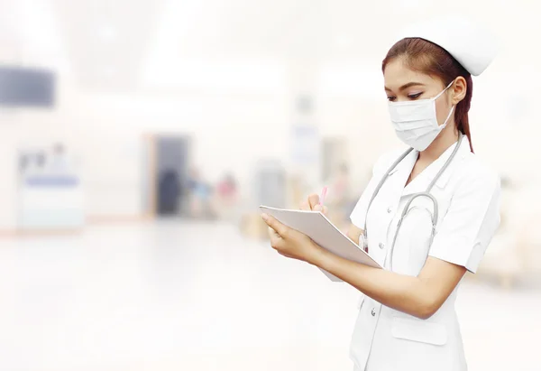 Nurse with stethoscope writing medical report in hospital