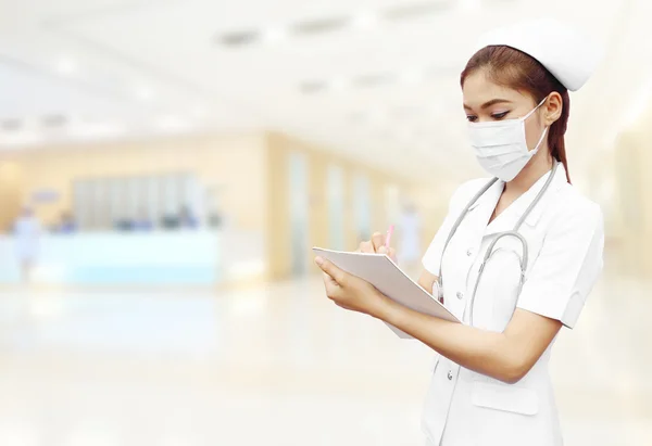 Nurse with stethoscope writing medical report in hospital