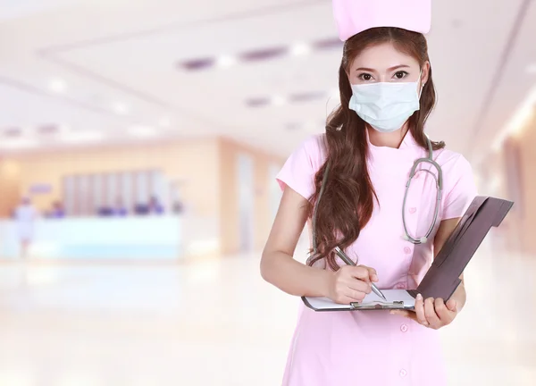 Female nurse writing medical report in hospital