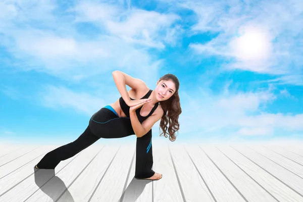 Woman doing yoga exercise on wood floor with sky