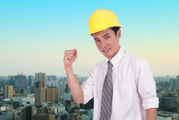 Happy engineer with arm raised, concept of successful, city back